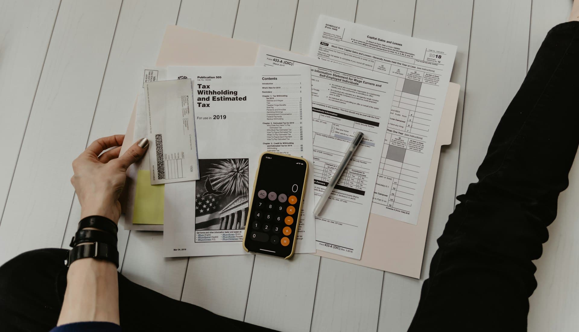 Laptop on a desk with budgeting or finance paperwork and a warm desk lamp, suggesting comparing monthly bills.